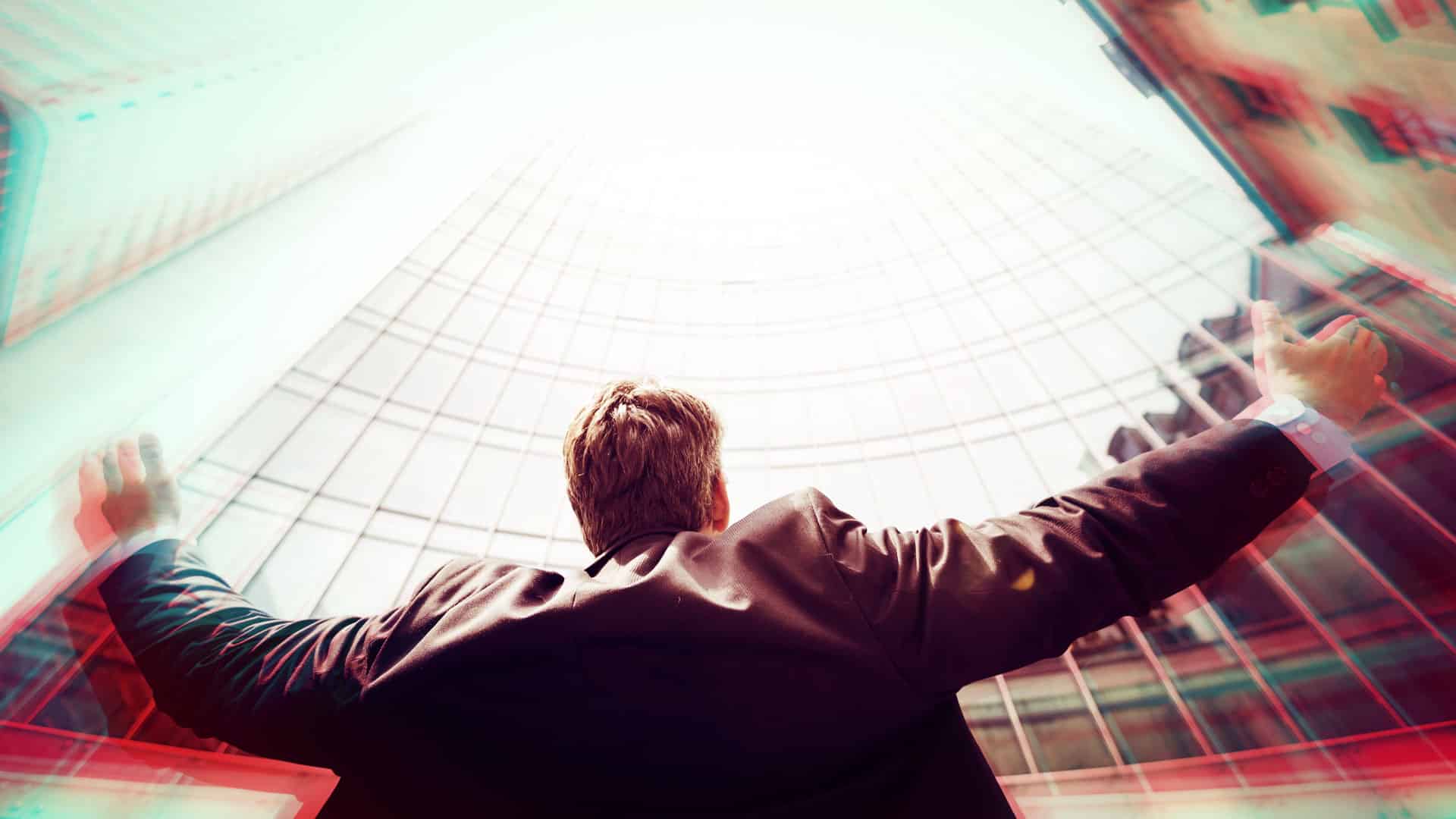 homme qui léve les bras vers le ciel regardant les buldings