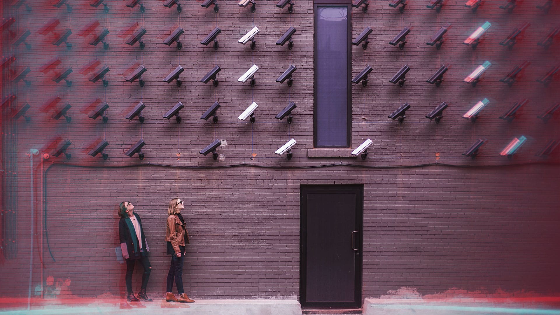 deux femmes dans la rue regardant un mur de caméra de surveillance